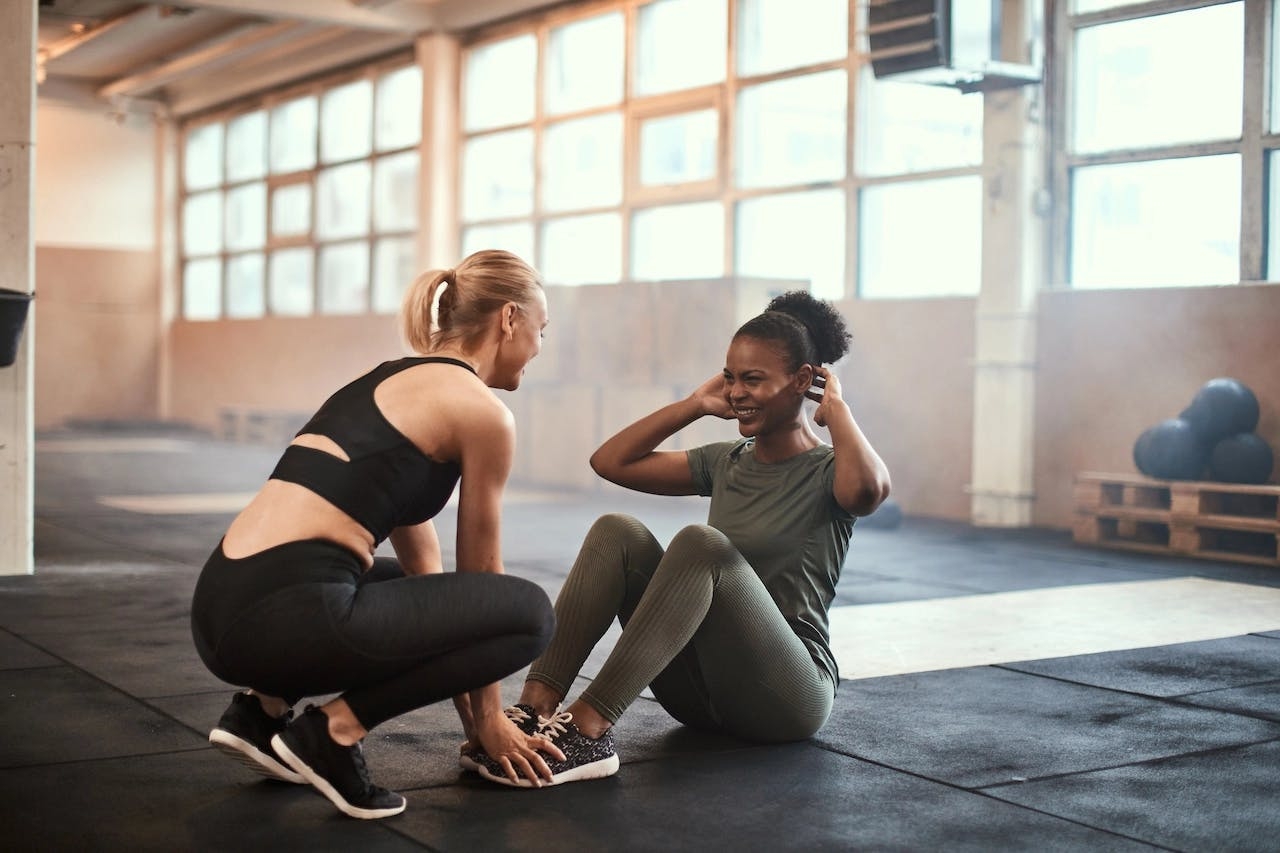 une coach sportif aide sa cliente à faire des abdominaux