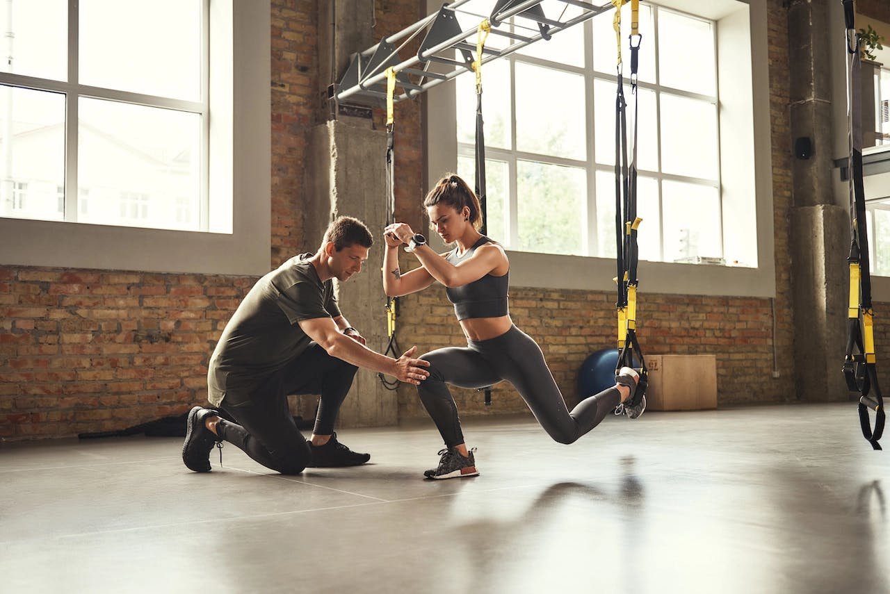 un coach sportif entraine sa cliente en trx